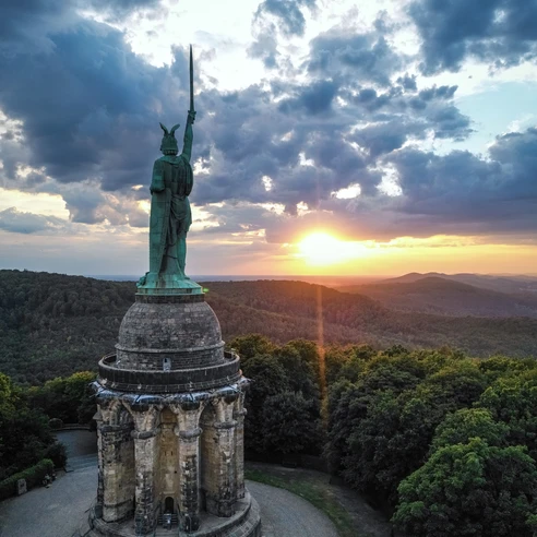 Hermannsdenkmal-Detmold-Teutoburger-Wald-Tourismus-D-Ketz-111-CC-BY-SA.jpg Das Hermannsdenkmal ragt monumental im Teutoburger Wald in der Abenddämmerung unter dramatischen Wolken auf.