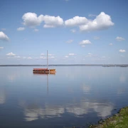 Steinhuder Meer.JPG Ein einzelnes Segelboot ruht friedlich auf einem weiten, stillen See unter klarem blauem Himmel.