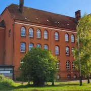 Volkshochschule_Silvana Dust_20230510_1980x1310.jpg Außenansicht der Volkshochschule Ratzeburg mit Eingangsbereich, Fenstern und umliegendem Gehweg sichtbar