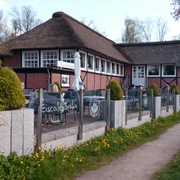 Eiscafé Bruhn_Silvana Dust_20230510_1980x1310.jpg Blick auf Sitzplätze vor einem Eiscafé, an denen Besucher sitzen