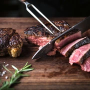 Dry aged beef im STEAKTRAIN - Gastronomie in Leipzig Auf einem Schneidebrett aus Holz wird das dry aged beef aus dem Restaurant STEAKTRAIN des Seaside Park Hotel aufgeschnitten