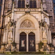 Tür der Stadtkirche St. Marien in Pirna Gotisches Kirchenportal mit zwei großen Holzflügeltüren, flankiert von steinernen Heiligenstatuen und einem Relief über dem Eingang.