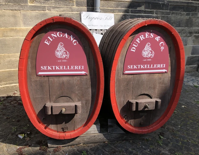 Sektkellerei Duprès Zwei große Holzfässer mit roten Schildern kennzeichnen den Eingang der Sektkellerei Duprès.