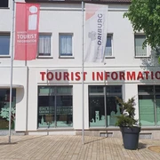 Bad Driburg_Tourist Information_Ausenansicht Tourist-Information in Bad Driburg mit klarer Beschilderung, Fahnen und einem bepflanzten Umfeld.