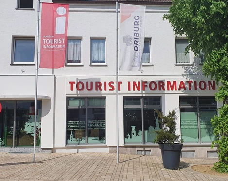 Bad Driburg_Tourist Information_Ausenansicht Tourist-Information in Bad Driburg mit klarer Beschilderung, Fahnen und einem bepflanzten Umfeld.