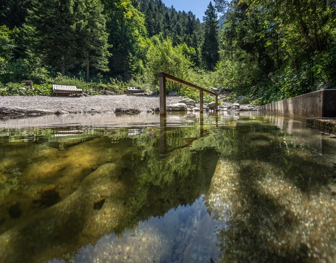Kneippbecken Farchant Kuhfluchtwasser im Vordergrund mit Stange zum Einhalten, im Hintergrund Bänke