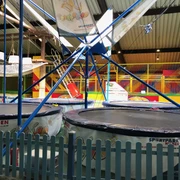 Trampolino in Hilden Große Trampoline umgeben von blauen Gittern in einer bunten Halle für sportliche Aktivitäten in Hilden.