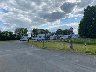 Festwiese Nienburg Wohnmobile stehen auf einer asphaltierten Fläche zwischen Bäumen unter einem bewölkten Himmel.