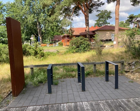 Ladestation für E-Bikes am Naturpark-Haus Mardorf, umgeben von Natur und mit angrenzendem Gebäude.