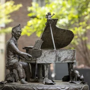 Jupp Schmitz memorial Skulptur von Jupp Schmitz am Klavier, umgeben von Bäumen.Sculpture of Jupp Schmitz at the piano, surrounded by trees.