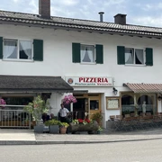 Pizzeria Ristorante Vesuvio - Außenansicht    Ein Wohnhaus mit einer Pizzeria im Erdgeschoss. Sitzmöglichkeiten vor dem Haus. Bunte Blumenkästen wirken einladend.