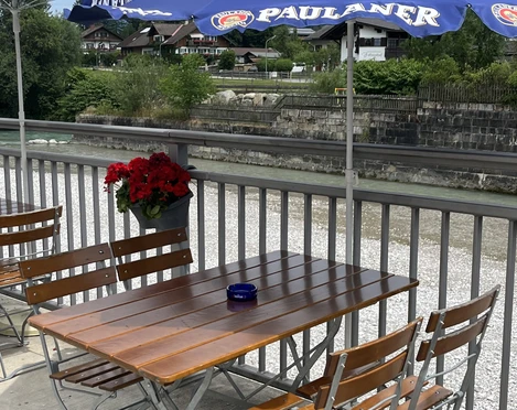 Pizzeria Restaurante Vesuvio - Außensitzbereich an der Loisach  Holztisch mit vier Stühlen unter einem Sonnenschirm direkt an der Loisach