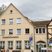 Touristinformation am Markt in Stadt Wehlen Zweistöckiges Gebäude mit der Aufschrift "Touristinformation", daneben Fachwerkhaus mit Restaurant "Elbterrasse", bewölkter Himmel.