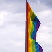 Cologne Pride Eine bunte Regenbogenflagge weht im Wind vor bewölktem Himmel.A colorful rainbow flag flies in the wind against a cloudy sky.