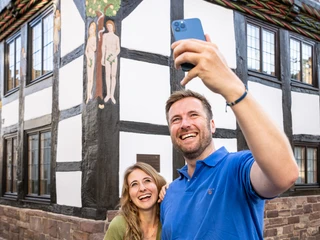 Hoexter-Adam und Eva-Haus-Stadt Hoexter-D. Ketz-2023-026.jpg Pärchen mach Selfie von Schnitzwerk von Adam und Eva am FachwerkhausCouple take selfie of carving of Adam and Eve on half-timbered house