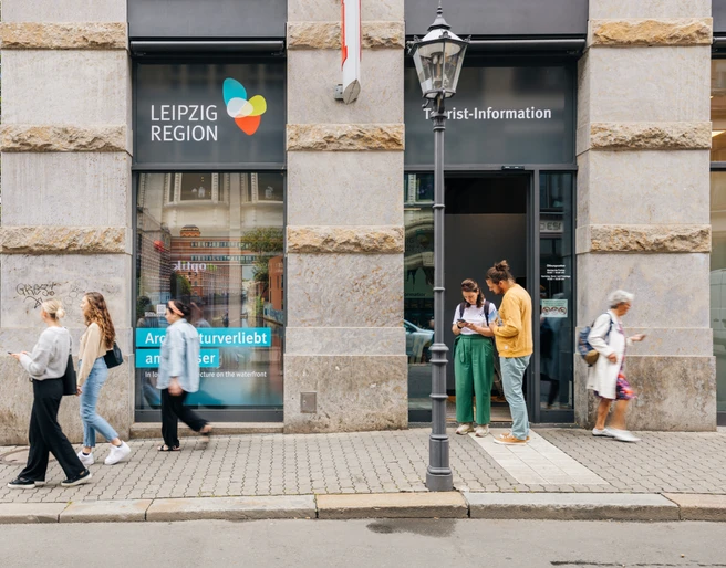 Eingang zur Tourist-Information Leipzig - Besucherberatung und Service Fassade und Haupteingang der Tourist-Information Leipzig in der Katharinenstraße 8, einige Touristen stehen vor dem Eingang und schauen sich Informationsmaterial anFasada i wejście główne do Informacji Turystycznej w Lipsku na Katharinenstraße 8, kilkoro turystów stoi przed wejściem i przygląda się materiałom informacyjnymThe façade and main entrance of the Leipzig Tourist Information Office, Katharinenstraße 8. Several tourists are standing in front of the entrance and looking at informational materialFaçade et entrée principale de l'office de tourisme de Leipzig au 8 rue Katharinenstraße, quelques touristes se tiennent devant l'entrée et consultent de la documentationFasáda a hlavní vchod do turistického informačního centra v ulici Katharinenstraße 8, před vchodem stojí několik turistů prohlížejících si informační materiál