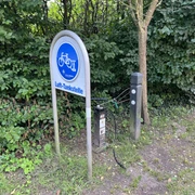 Lufttankstelle Martfeld Fahrrad-Lufttankstelle am Waldrand mit Manometer und Reifenventil, umgeben von grünem Laub.