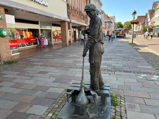 Glasbläser Eine Statue eines Glasbläsers auf einem Marktplatz, der konzentriert Glas formt.