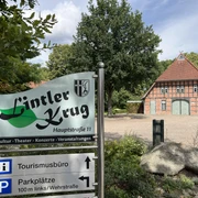 Lintler Krug Der Lintler Krug ist ein traditionelles Backsteingebäude mit begrüntem Vorplatz und großem Baum.