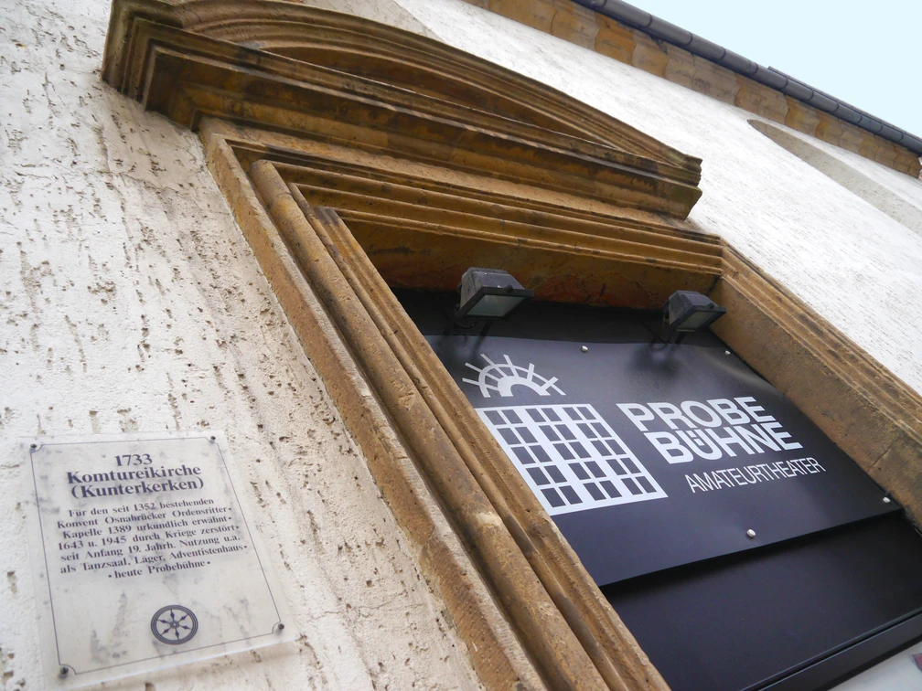 Eingang zur Probebühne Osnabrück, ein Amateur-Theater, mit historischem Kirchenportal und Infotafel.