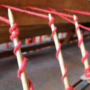 Tuchmacher Museum Bramsche im Osnabrücker Land Spindeln mit rotem Faden, bereit zur Verarbeitung in einer traditionellen Webmaschine.