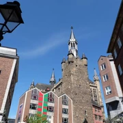 Granusturm Der viereckige Granusturm steht in der Mitte historischer Gebäude vor blauem Himmel.
