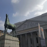 Vor dem Theater Aachen steht die Statue eines Pferdes auf einem hohen Sockel.