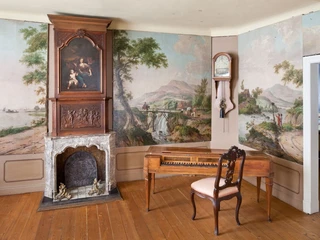 Ausstellungsraum im Couven Museum mit kunstvollem weißem Marmorkamin und Landschaftswandgemälden sowie einem antiken Cembalo auf Holzboden.