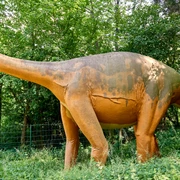 Modell eines Megalosauriers an den Saurierfährten in Bad Essen – Barkhausen. Lebensgroße Dinosaurierfigur in einem von Bäumen umgebenen Grünstreifen.