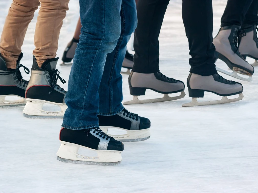 100,5 Arena - Eissporthalle Mehrere Personen in verschiedenen Schlittschuhen gleiten auf Eis.