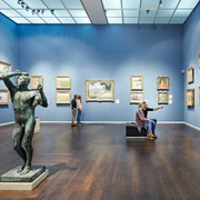 Wallraf-Richartz-Museum & Fondation Corboud Ein lichtdurchfluteter Museumsraum mit blauen Wänden zeigt Bilderrahmen, eine Statue im Vordergrund.A light-flooded museum room with blue walls shows picture frames and a statue in the foreground.
