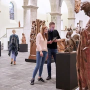 Museum Schnütgen Cologne Besucher*innen betrachten Skulpturen in einem hell erleuchteten Raum des Museum Schnütgen in Köln.Visitors view sculptures in a brightly lit room at the Museum Schnütgen in Cologne.