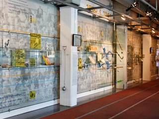 German Sport & Olympia Museum Innenansicht des Sportmuseums mit Ausstellungstafeln und Laufbahn, historische Aufnahmen im Hintergrund.Interior view of the sports museum with exhibition boards and running track, historical photos in the background.