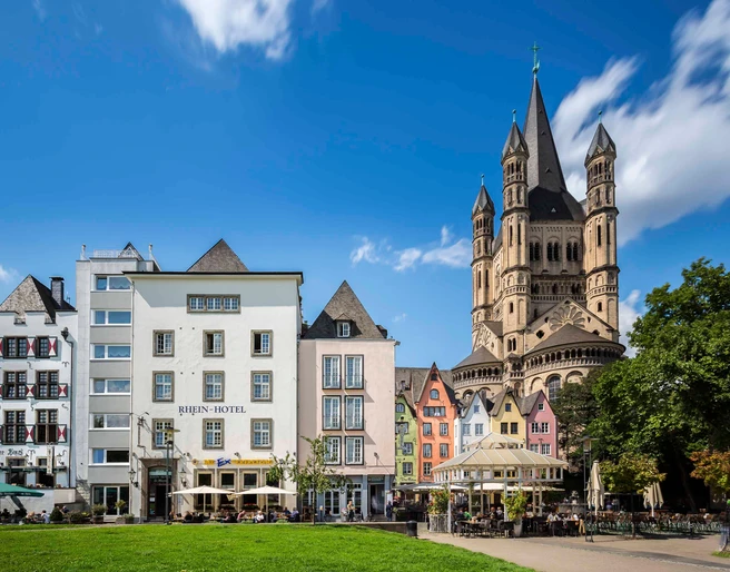 Cologne old town Rhine bank Die Kölner Altstadt am Rheinufer zeigt malerische bunte Häuser und ist von der imposanten Groß St. Martin Kirche überragt, vor strahlend blauem Himmel.Cologne's old town on the banks of the Rhine features picturesque colorful houses and is dominated by the imposing Gross St. Martin Church, set against a bright blue sky.
