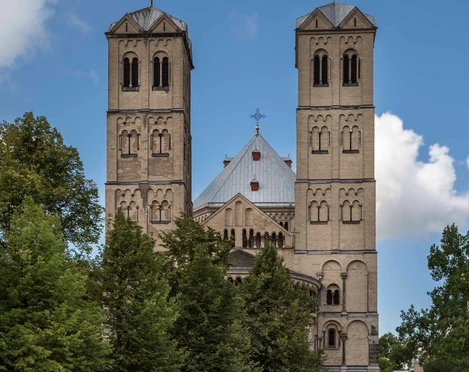 Saint Gereon Romanische Kirche Sankt Gereon in Köln mit zwei markanten Türmen, umgeben von grünen Bäumen.Romanesque church of St. Gereon in Cologne with two striking towers, surrounded by green trees.