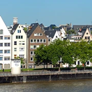 Pegel Köln Reihen schiefer Fachwerkhäuser mit spitzen Dächern säumen das Rheinufer unter strahlend blauem Himmel.Rows of crooked half-timbered houses with pointed roofs line the banks of the Rhine under a bright blue sky.