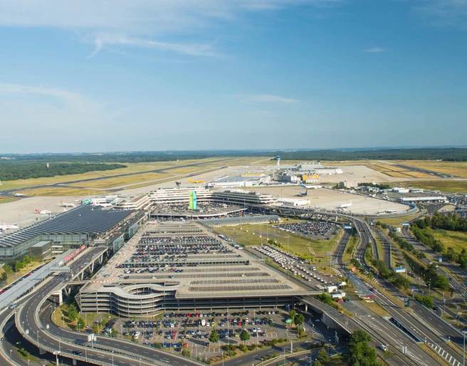Köln Bonn Airport Luftaufnahme des Flughafens Köln/Bonn mit Terminalgebäuden, Parkplätzen und Start-/Landebahnen bei blauem Himmel.Aerial view of Cologne/Bonn Airport with terminal buildings, parking lots and runways under a blue sky.