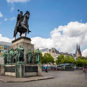 Equestrian statue of King Frederick William III. Denkmal des preußischen Königs auf einem Pferd, umringt von Statuen in belebter Altstadt mit Domblick.Monument to the Prussian king on a horse, surrounded by statues in a lively old town with a view of the cathedral.