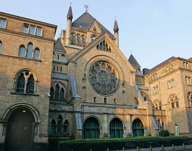 Synagogue Romanische Fassade der Synagoge aus Sandstein mit großen, runden Fenstern und spitzen Türmen.Romanesque façade of the synagogue made of sandstone with large, round windows and pointed towers.