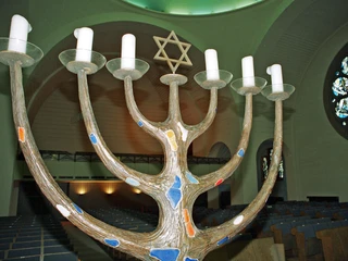 Synagogue Der Bildausschnitt zeigt eine kunstvoll gestaltete Menora mit sechs Armen und einem Davidstern im Hintergrund in der Synagoge an der Roonstraße in Köln.The image detail shows an artistically designed menorah with six arms and a Star of David in the background in the synagogue on Roonstraße in Cologne.