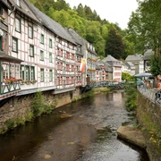 Traditionelle Fachwerkhäuser entlang eines Flusslaufs mit blühenden Blumenkästen an den Fenstern.