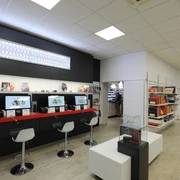 Fotohaus Preim Modernes Fotogeschäft mit langer Theke, auf der mehrere Bildschirme stehen und Stühle daneben.