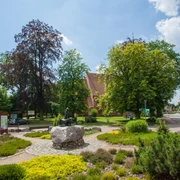 bispingen-ortsmitte Die örtliche Beschreibung des Bildes von der Bispinger Ortsmitte könnte wie folgt aussehen:Ein malerischer Platz in der Ortsmitte von Bispingen mit gepflegten Grünflächen, Bänken und einem großen Baum. Im Vordergrund ist eine steinerne Skulptur zu sehen, während im Hintergrund bunte Gebäude den Charme des Dorfes unterstreichen.