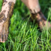 fuss-barfusspark-gras Ein nackter Fuß steht im grünen Gras, bedeckt mit natürlichem, heilendem Moor.