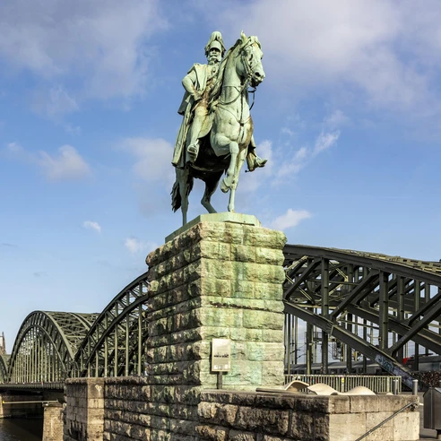 Equestrian statue of Kaiser Wilhelm I. Ein majestätisches Reiterstandbild von Kaiser Wilhelm I., im Hintergrund der Kölner Dom und die Hohenzollernbrücke.A majestic equestrian statue of Kaiser Wilhelm I, with Cologne Cathedral and the Hohenzollern Bridge in the background.