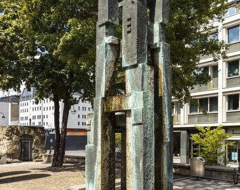 Theo Burauen Fountain Der Theo-Burauen-Brunnen in Köln zeigt eine moderne, bronzene Skulptur mit gestapelten Blöcken.The Theo Burauen Fountain in Cologne features a modern, bronze sculpture with stacked blocks.