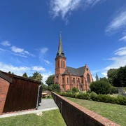 St. Jakobi-Kirche zu Wittlohe Die rote Backstein-St. Jakobi-Kirche in Wittlohe erhebt sich vor einem klaren blauen Himmel.