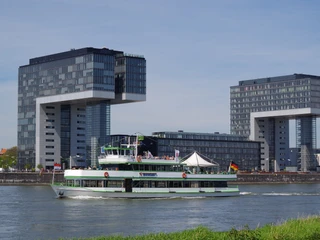 Kölntourist passenger boat service Blick auf den Rhein in Köln mit einem vorbeifahrenden Ausflugsschiff vor den markanten Kranhäusern.View of the Rhine in Cologne with a passing excursion boat in front of the striking crane buildings.