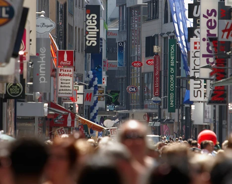 Hohen Straße Hohe Straße in Köln, belebt mit Einkaufenden. Verschiedene Geschäfte und farbige Werbeschilder flankieren den belebten Weg. Direkte Straßenansicht mit im Hintergrund sichtbaren Gebäuden.Hohe Straße in Cologne, bustling with shoppers. Various stores and colorful advertising signs flank the busy street. Direct street view with buildings visible in the background.