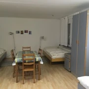 Monteurzimmer mit mehreren Betten, einem Tisch und Stühlen